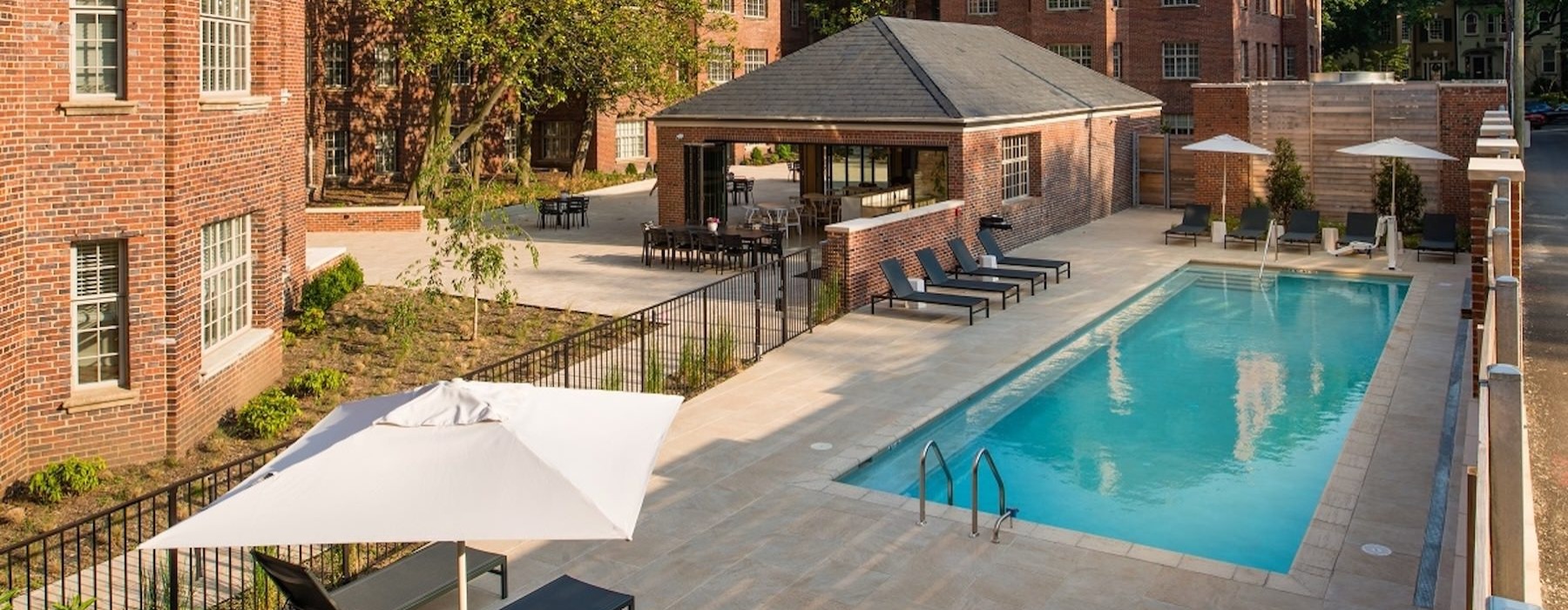 a pool with a deck and chairs by it and umbrellas by it