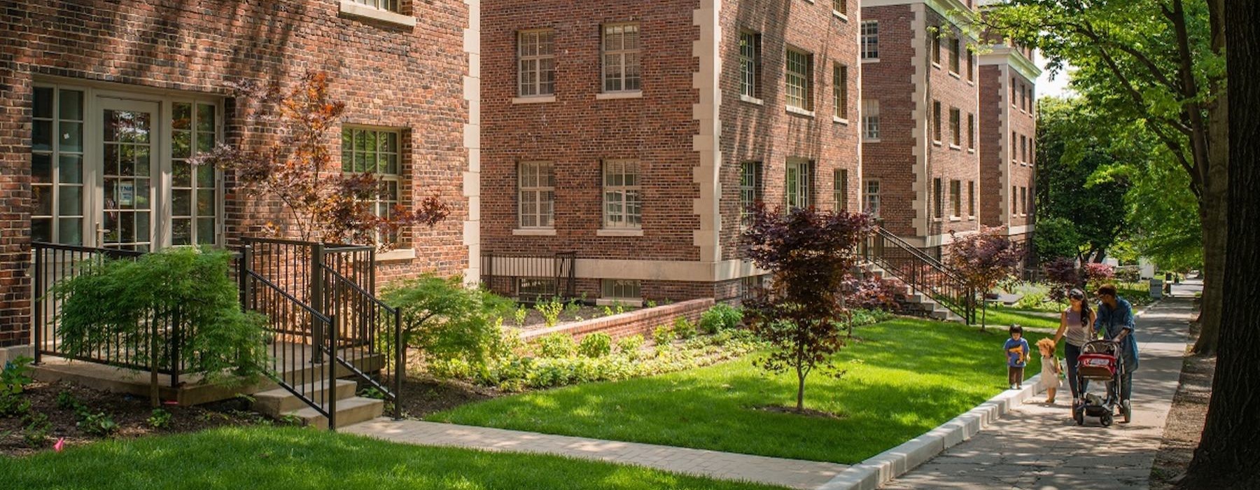a brick building with a walkway and trees in front of it